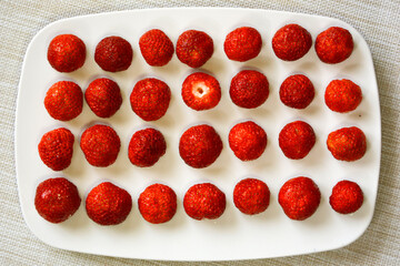 Strawberries lie in a row on a plate. The view from the top. Red berries close-up.