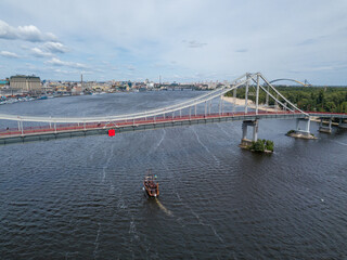 Aerial drone view. A pirate motor boat sails under bridge along the Dnieper River in Kiev.
