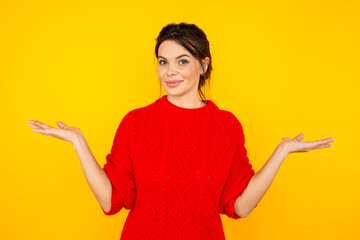 Handsome woman in the red sweater isolated in yellow studio