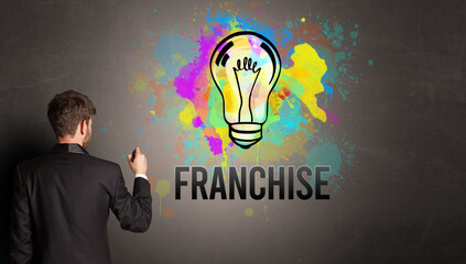 businessman drawing colorful light bulb with FRANCHISE inscription on textured concrete wall, new business idea concept