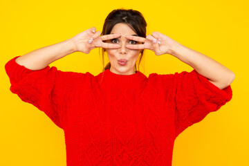 Pretty woman in the red sweater having fun in the yellow studio isolated