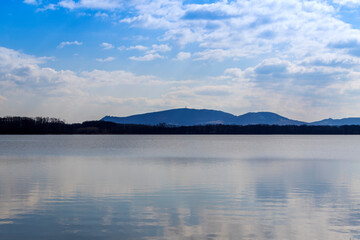 Lake Mušov with a view of the Pálava region in the Czech Republic. In the background is a blue sky with clouds.