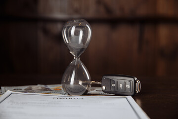 Car keys and hourglass on the signed agreement document.