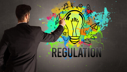businessman drawing colorful light bulb with REGULATION inscription on textured concrete wall, new business idea concept