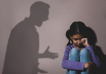 Child abuse. Father yelling at his daughter. Shadow of man on wall