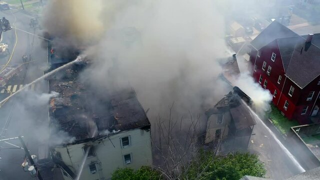 Smoke Fills the Air in the Aftermath of an Apartment Building Fire with Firefighters on Site, Panning Drone Shot