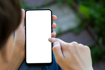 hand holding the black smartphone blank screen with modern frameless design on nature background