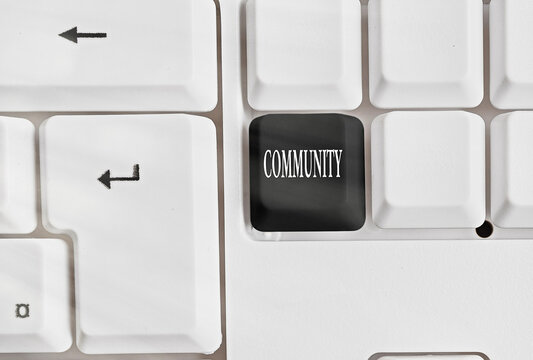 Conceptual hand writing showing Community. Concept meaning group of showing with a common characteristics living together Colored keyboard key with accessories arranged on copy space
