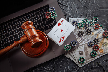 Judge gavel, money banknotes and playing cards on computer keyboard, legal rules for online gambling concept.