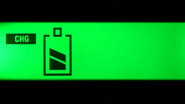 Close up of liquid crystal monochrome green display of charger  with one battery charge level indicators appearing in sequence. Copy space background