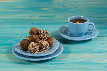 A portion of homemade energy balls and a Cup of tea on a blue wooden table. Delicious and healthy dessert for Breakfast. Lifestyle