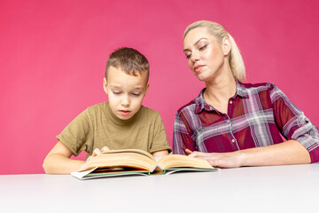 Mother helping her son with homework over isolated pink background. Distant education.