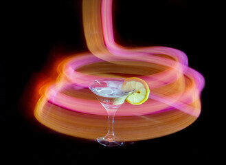 Glass of cocktail in a dark room and neon light trails