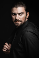 Strict male portrait. The guy in the classic black suit. Half face in the light.