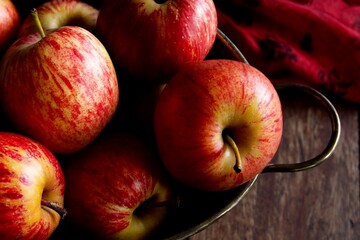 Top down view of a bowl of red apples on a wooden table
