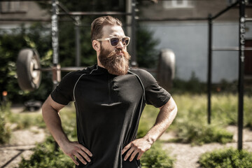 Fototapeta premium Confident muscular young man standing with arms crossed outdoors.