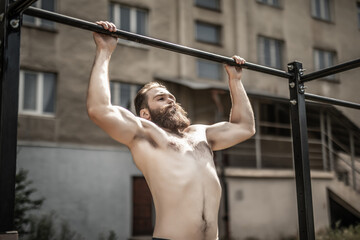 Fitness, sport, exercising, training and lifestyle concept. Young man doing pull ups on horizontal...
