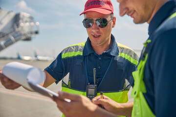 Two focused airport workers scrutinizing after-landing checklists