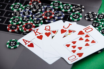 Obraz premium Different of cost casino chips stacking and playing cards on a laptop. Bet at game and win.