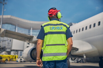 Airport worker looking at a parked plane