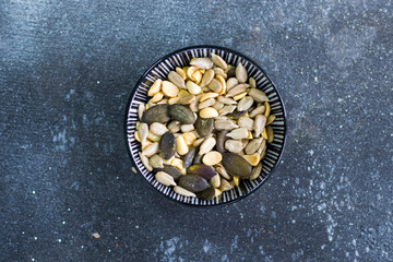 Sunflower and pumpkin seeds in bowl on the blue background. Large group of seeds. Snack and appetizer.