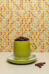Lime green coffee cup and saucer filled with fresh coffee beans with bright and colourful patterned background 