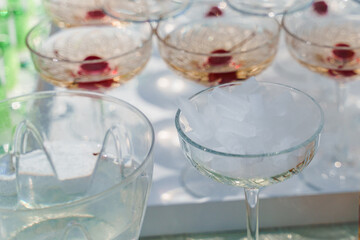 Dry ice cubes in glass cup close-up near pyramid of champagne. Dry ice for smoke effect when waiter puts ice into sparkling wine glass.