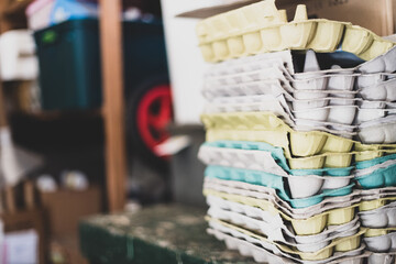 Stacks of multi-coloured cardboard egg cartons in a shed