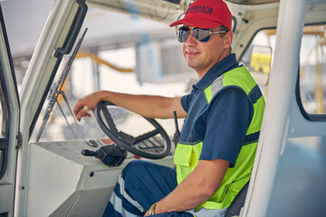 Smiling airport worker sitting behind the steering wheel