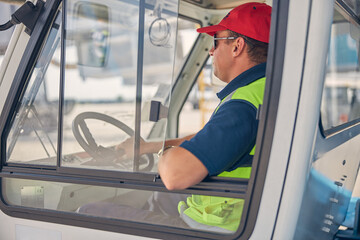 Male worker in sunglasses driving a car