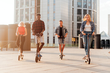 interracial group of friends ride electric scooters in the city, multiracial youth use electric vehicles © Богдан Маліцький