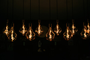 Lighting decor. Retro light bulb filament hanging close up. Illuminated.