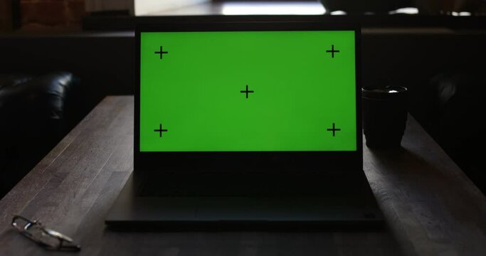 Laptop With Green Screen and Tracking Dot. Dark office. A Man's Hand Opens The Laptop Screen