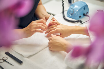 Woman having nails filed by professional in salon