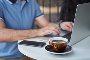 Male working on notebook in street cafe