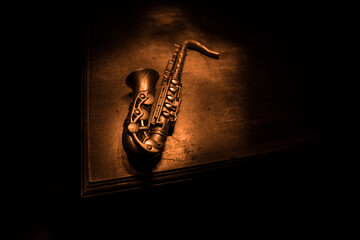 Alto gold sax miniature with colorful toned light on foggy background. Saxophone music instrument in lowlight. Selective focus - obrazy, fototapety, plakaty