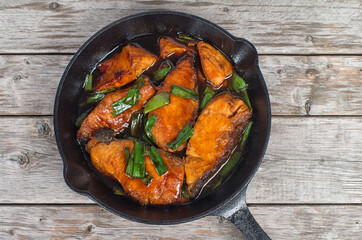 Vietnamese simmered salmon in cast iron pan on a wooden table