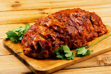 Classic meatloaf on a cutting board on a wooden background. In the background are red and yellow cherry tomatoes, parsley, ears of wheat