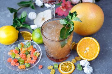 Cold refreshing pineapple cocktail with lime and mint for a hot summer day on a gray background decorated with candied fruit, mint and pineapple cubes. mojito idea, homemade lemonade with ice cubes