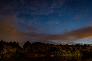 Naklejka na ściany i meble Evening landscape: first stars and a comet Neowise over a forest lake just after sunset. Long exposure night landscape. 
