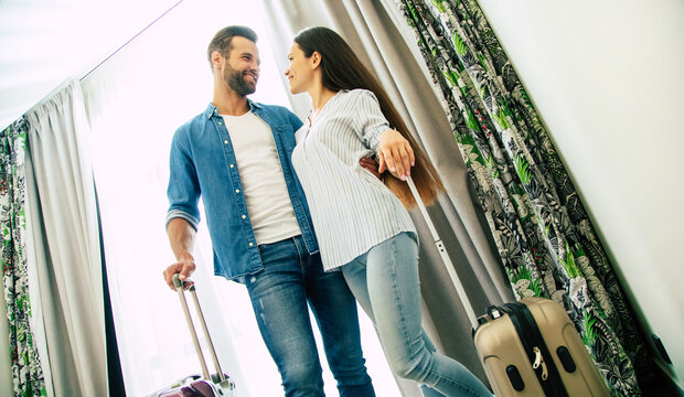 Young beautiful happy excited couple in love with suitcases in a modern hotel during vacation