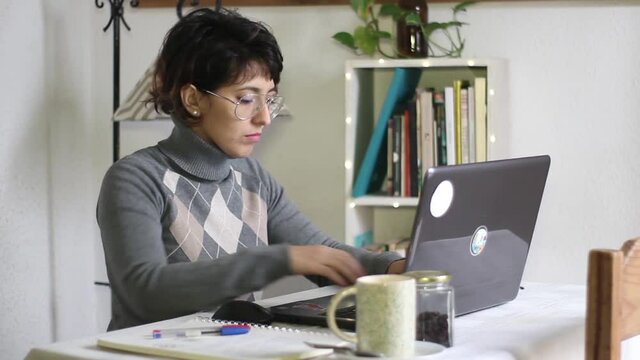 Young hispanic brunette woman with vintage glasses in front of laptop studying or taking online class during quarantine 