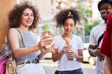 Cheerful young people eating fast food outdoors