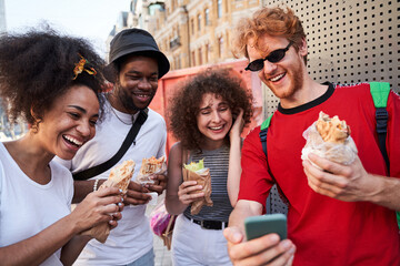 Happy young company with smartphone and hot dogs