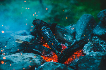 Vivid smoldered firewoods burned in fire closeup. Atmospheric background with orange flame of...