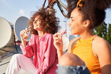 Obraz premium Jolly young women enjoying meals and drinks on roof