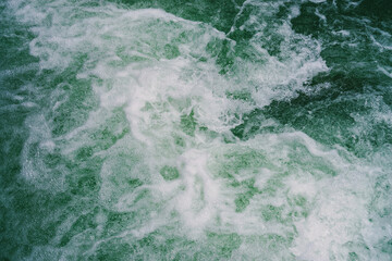 Green water surface with bubbles close-up. Background of green soda drink water. Nature texture of sea surf. Refreshing mint drink with vitamins. Natural backdrop of ocean surf. Fortified water.