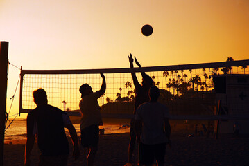Young adults play a friendly game of beach volleyball in Laguna Beach at sunset