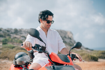 A man sits on a quad in the mountains