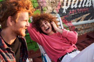 Merry young couple relaxing on deckchairs outdoors